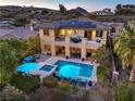 Expansive backyard with a sparkling pool, spa, outdoor seating, covered patio, and upper balcony with mountain views at 79 Rezzonico Dr, Henderson, NV 89011