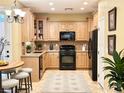 Well-lit kitchen features wooden cabinetry, black appliances, tile flooring, and modern decorative elements at 8477 Orly Ave, Las Vegas, NV 89143