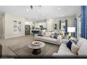 Bright, open living room with modern decor, wood-look flooring, an adjacent kitchen, and lots of natural light at 325 Talladega Ct # Lot 6, Henderson, NV 89015