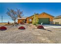 Home's charming front elevation features a desert landscape, spacious driveway, and an attached garage at 3424 Mount Charleston Dr, Pahrump, NV 89048