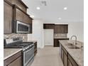 Modern kitchen boasts granite countertops, stainless steel appliances, and stylish dark cabinetry for a sleek design at 367 Wilford Springs St, Henderson, NV 89014