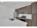 Modern kitchen with stainless steel appliances, white countertops, and dark brown cabinets at 393 Desert Cadence St, Henderson, NV 89011
