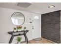 Entryway with wood-look floors, brick accent wall, entry table, and round mirror at 3991 Shadow Wood Ave, Las Vegas, NV 89121