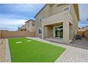 Spacious backyard featuring synthetic grass, a covered patio, and a brick-paved area, perfect for outdoor living at 8866 Mountain Lion Ave, Las Vegas, NV 89166