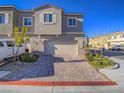 Inviting townhouse featuring a two-car garage, brick-paved driveway, and neatly arranged front yard landscaping at 10768 Ditchburn Ct, Las Vegas, NV 89166