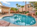Backyard pool featuring a rock waterfall, lounge chairs, and surrounding palm trees at 2293 Bull Lake Dr, Henderson, NV 89052