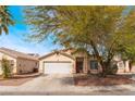 Inviting single-story home with a large front yard, mature tree, and a convenient two-car garage at 2410 Morocco Ave, North Las Vegas, NV 89031