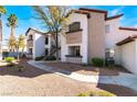 Two-story condo building featuring balconies, earth-toned stucco, mature trees, and desert landscaping at 2615 W Gary Ave # 1089, Las Vegas, NV 89123