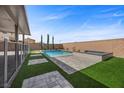 A backyard pool and jacuzzi bordered with stone, turf and tall trees in a fenced-in yard at 4040 Beech Fern Ave, North Las Vegas, NV 89084