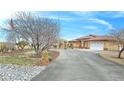 Inviting desert home with circular driveway, stone landscaping, and well-manicured lawn at 1830 E Fuchsia St, Pahrump, NV 89048