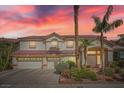 Inviting two-story home with a three-car garage, desert landscaping, and a red tile roof against a colorful sunset at 442 Beardsley Cir, Henderson, NV 89052