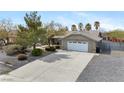Front exterior featuring desert landscaping, a two-car garage, and a concrete driveway at 6860 Stubblefield Dr, Pahrump, NV 89061