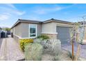 Well-manicured home exterior with a lush garden, brick driveway, and a charming, modern gray color scheme at 9739 Douglas Fir St, Las Vegas, NV 89143