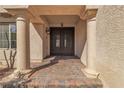 Close-up of the front door featuring paver steps, elegant pillars, an iron security door and decorative outdoor lighting at 9967 Pipestone St, Las Vegas, NV 89141