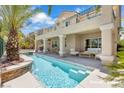 Backyard features a modern pool with waterfall feature, seating area, and covered patio at 3088 Via Flaminia Ct, Henderson, NV 89052