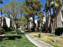 Scenic walkway through the well-maintained grounds with grass, mature trees and condo buildings at 6250 W Flamingo Rd # 143, Las Vegas, NV 89103