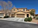 Tan two-story home featuring a two-car garage, manicured front yard with shrubs, and a well-maintained desert landscape at 6656 Fort William St, North Las Vegas, NV 89084