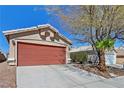 Side view of a home featuring a terracotta garage door and desert landscaping at 8472 W Gilmore Ave, Las Vegas, NV 89129
