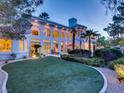 Expansive backyard with lush lawn, palm trees, well-maintained landscaping, and exterior lighting at 10 Innisbrook Ave, Las Vegas, NV 89113
