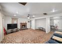 An open living room with a fireplace, ceiling fan, carpeting, and lots of space for entertaining at 1160 Huracan St, Pahrump, NV 89048