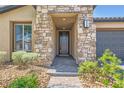 Close up of the home's entrance with stone pillars, a paved walkway, and neutral landscaping at 243 Sun Glaze Ave, Henderson, NV 89011