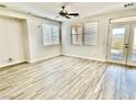 Bright living room featuring gray wood floors, ceiling fan, and double doors to the backyard at 2773 Drumlanrig St, Henderson, NV 89044