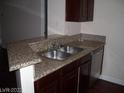 Galley kitchen featuring a stainless sink, granite countertop, and wood cabinets at 5130 S Jones Blvd # 108, Las Vegas, NV 89118