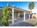 Covered backyard patio with a dining set, lush climbing plants, and a brick paver walkway, ideal for relaxation at 7913 Rushmore Ave, Las Vegas, NV 89131