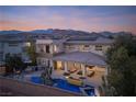 Beautiful aerial view of a luxury home, featuring a custom pool, covered patio, and mountain views at 80 Glade Hollow Dr, Las Vegas, NV 89135
