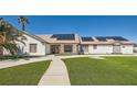 Inviting single-story home with solar panels, a well-maintained lawn, and mature palm trees at 8515 Belcastro St, Las Vegas, NV 89113