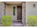 Close up of a well landscaped home entrance with stone accents around the door and a decorative light fixture at 8564 Scalpay St, Las Vegas, NV 89166