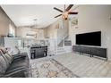 This living room has a vaulted ceiling, a ceiling fan, stairs with patterned risers and a large TV screen at 8725 Hawk Canyon St, Henderson, NV 89074