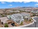 Aerial view of a neighborhood showcasing a gray home with manicured lawns and mountain views at 2616 Tolmezzo St, Henderson, NV 89044