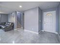 Bright living room featuring sleek tile flooring, a staircase, and a front door with glass accents at 5364 Awbury Ave, Las Vegas, NV 89110