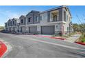 Townhome exteriors showing private garages and colorful shutters and doors and manicured landscaping on a sunny day at 7204 N Decatur Blvd, North Las Vegas, NV 89131