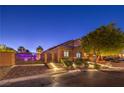 Charming home featuring brick accents, landscaped front yard, and iron gate, illuminated by step lighting at 7311 Velvet Sky St, Las Vegas, NV 89131