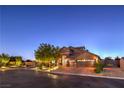 A beautiful exterior view of a home with brick-paved driveway, a mature tree and elegant landscaping in a well-lit cul-de-sac at 7311 Velvet Sky St, Las Vegas, NV 89131