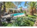 Lush backyard oasis featuring a sparkling pool, covered patio, and verdant landscaping at 8120 Neptune Beach Ave, Las Vegas, NV 89128