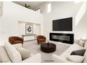 Staged living room with a fireplace, large screen tv, modern sofas and chairs, and high ceilings at 9993 Birch Knoll Ave, Las Vegas, NV 89166