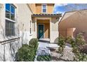 Inviting home entrance featuring a classic blue door adorned with a wreath, complemented by well-manicured landscaping at 1112 Adobe Creek Ct, North Las Vegas, NV 89084