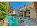 A backyard view of a pool and attached spa, with an outdoor kitchen and a view of the home at 7420 Enchanted Hills Ct, Las Vegas, NV 89129