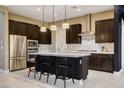 Stylish kitchen with dark wood cabinets, stainless appliances, white countertop island, and modern lighting at 10172 Bismarck Palms Ave, Las Vegas, NV 89166