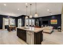 Open-concept living space with kitchen island, dining area, and comfortable seating under modern pendant lighting at 10172 Bismarck Palms Ave, Las Vegas, NV 89166