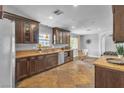 Charming kitchen with dark wood cabinets, tiled floors, granite countertops, and stainless steel appliances at 4678 Saddle Pl, Las Vegas, NV 89119