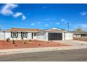 Charming single-story home featuring a well-manicured yard and a black garage door at 5200 Longridge Ave, Las Vegas, NV 89146