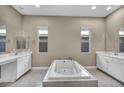 Spa-like primary bathroom boasts a soaking tub, dual vanities, and tiled floors surrounded by natural light at 10348 Bressana Dr, Las Vegas, NV 89135