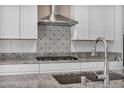 Bright modern kitchen features stainless hood, gas cooktop, white cabinets, granite counters, and a designer backsplash at 10348 Bressana Dr, Las Vegas, NV 89135