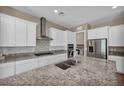Gourmet kitchen features stainless steel appliances, double ovens, a granite island, white cabinets, and tile backsplash at 10348 Bressana Dr, Las Vegas, NV 89135