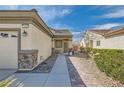 Home exterior features a decorative stone accent, well-manicured shrubs, and a quaint entryway at 2409 Garganey Ave, North Las Vegas, NV 89084