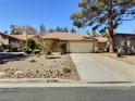 Beautiful front exterior features a two-car garage, desert landscaping, and a mature tree providing shade at 3619 Edinburgh Dr, Las Vegas, NV 89103